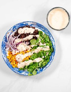 a blue and white bowl filled with food next to a glass of milk