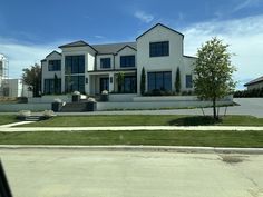 a large white house sitting on the side of a road next to a lush green field