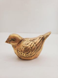 a gold colored bird figurine sitting on a white surface