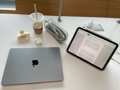 an apple laptop computer sitting on top of a white table next to a cup of coffee