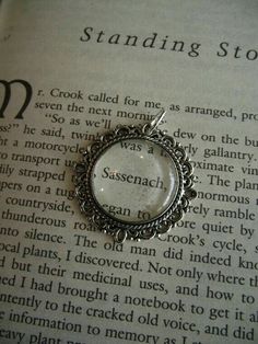 a close up of an open book with a necklace on it's side and the words standing stone written in cursive writing