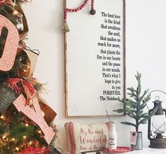 a decorated christmas tree in front of a framed sign that reads, the best love is always