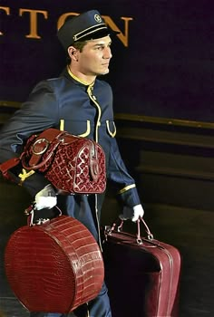 a man in uniform carrying two pieces of luggage