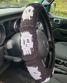 the steering wheel cover is knitted with skulls and bones in white, black, and gray