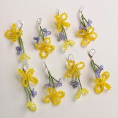 small crocheted flowers are arranged in rows on a white surface, with tiny hooks attached to them