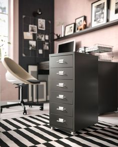 a filing cabinet sitting on top of a black and white checkered floor next to a chair