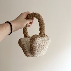 a hand holding a crocheted purse in the air