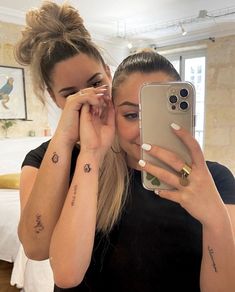 two women are taking a selfie with their cell phones in front of the camera