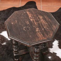 an old wooden table sitting on top of a cowhide rug