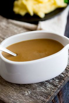 a white bowl filled with soup sitting on top of a wooden table