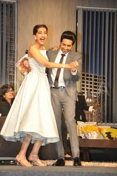 a man and woman dancing on stage at a formal event with people in the background