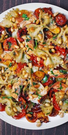 a white plate topped with pasta and veggies on top of a wooden table