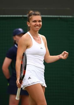 a woman holding a tennis racquet on top of a tennis court with two other people in the background