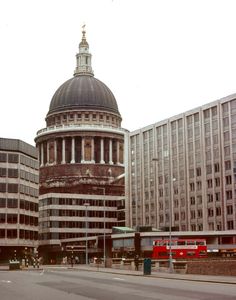 an old building with a dome on top in the middle of a city street next to tall buildings