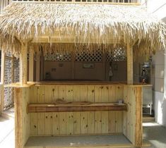 an outdoor bar made out of wood and straw with a thatch roof over it