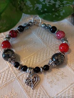 Heart charm beaded bracelet in red and black colors with metal charm. Made with various beads, mainly acrylic.  Toggle clasp . 7.5 inches long. Metal Heart-shaped Beaded Bracelets For Valentine's Day, Heart-shaped Metal Beaded Bracelets For Valentine's Day, Metal Heart-shaped Beaded Bracelet For Valentine's Day, Silver Beaded Charm Bracelet With Heart Shape, Silver Beaded Heart Charm Bracelet, Silver Beaded Heart-shaped Charm Bracelet, Silver Heart-shaped Beaded Charm Bracelet, Elegant Heart-shaped Bracelets With Colorful Beads, Silver Heart-shaped Beaded Bracelet