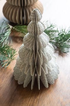 a knitted christmas tree sitting on top of a wooden table next to pine cones