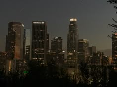 the city skyline is lit up at night, with skyscrapers in the foreground