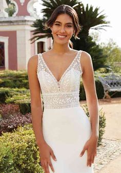 a woman in a white wedding dress posing for the camera with her hands on her hips