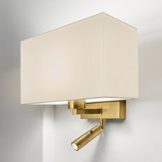 a wall light with a white shade on it's side and a gold arm