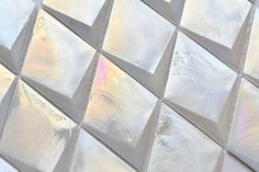 a close up view of a glass tile wall with white and silver squares on it