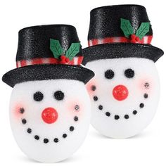 two snowmen with hats and holly leaves on their heads, one wearing a black hat