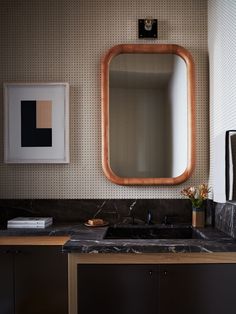 a bathroom with a sink, mirror and pictures hanging on the wall above it's counter