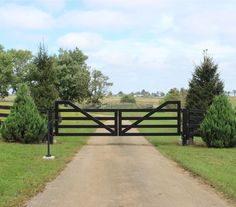 a gated driveway leading to a grassy field