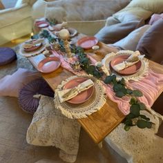 the table is set with pink plates and place settings