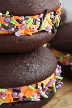 three chocolate donuts with sprinkles and candy on top are stacked up