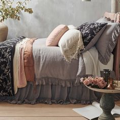 a bed sitting in a bedroom next to a table with flowers on top of it