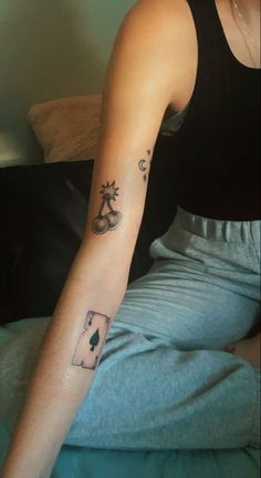 a person sitting on a bed with a tattoo on their arm and the other arm