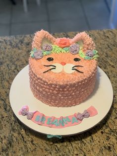 there is a cake that looks like a cat on the plate with name written on it