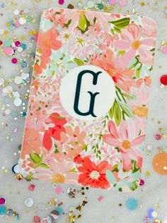 a card with the letter g on it surrounded by confetti