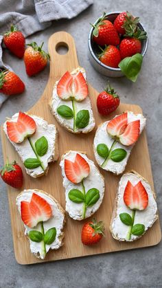 strawberries are arranged on top of crackers with cream cheese and fresh basil leaves