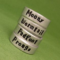 three silver rings with words on them sitting on a green surface, one saying money won't fall and the other saying proof