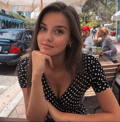 a woman sitting at a table with her hand on her chin and looking off to the side