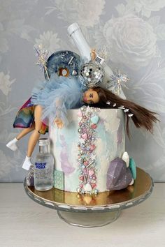 there is a cake with a doll on it and other items in the top tier