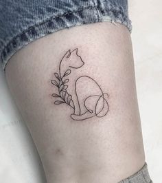 a small cat tattoo on the ankle with leaves and flowers around it's ankles