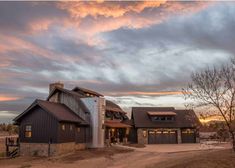 a large house sitting in the middle of a dirt road under a cloudy sky at sunset