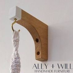 a wooden hook is attached to the wall with a white rope hanging from it's end