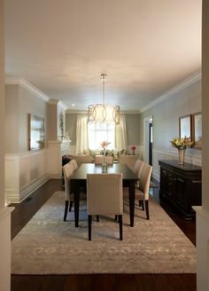 a dinning room table and chairs in front of a window with white drapes