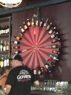 a man standing in front of a bar filled with liquor bottles and glasses on the wall