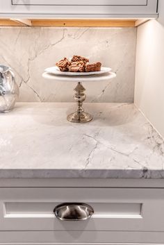 a white marble counter top under a microwave oven with cookies on it and a teapot