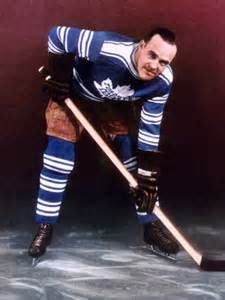 an old photo of a hockey player in uniform and holding a stick on the ice