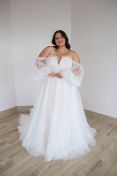 a woman in a white dress posing for the camera with her hands on her hips