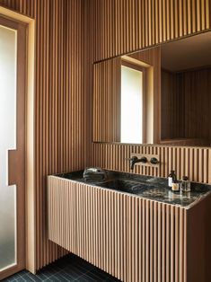 a bathroom sink sitting under a mirror next to a wooden paneled wall and floor