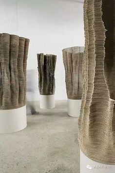 three tall white vases with different types of fabric wrapped around them on pedestals