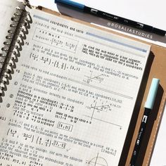 an open notebook with some writing on it next to a pen and calculator