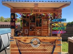 a small wooden bar with many signs on the front and back wall, along with a boat in the background